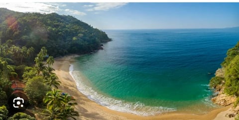 Aerial view of a tropical cove with sandy beach, turquoise waters, and lush green cliffs